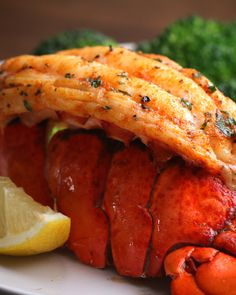 lobster, broccoli and lemon on a white plate with some sort of garnish