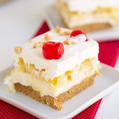 a piece of cake with white frosting and cherries on top is sitting on a plate