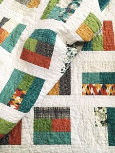 a close up of a quilt on a bed with many different colored squares and shapes