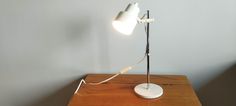 a desk lamp sitting on top of a wooden table next to a white light bulb