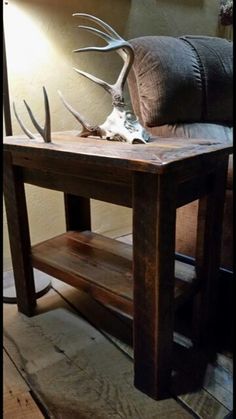 a wooden table with antlers on it in front of a wall and a couch