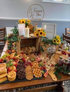 a wooden table topped with waffles, fruit and other foods on top of it