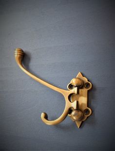 an antique brass hook on a gray wall