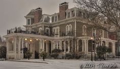 an old victorian style house with snow on the ground