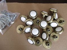 a bunch of white knobs sitting on top of a cardboard box next to some screws