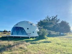 a large dome like structure sitting on top of a lush green field under a blue sky