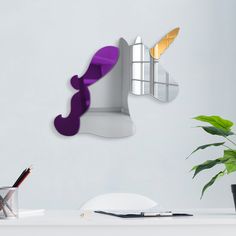 a white desk with a purple and yellow object on the wall next to a potted plant