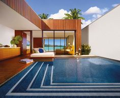 an indoor swimming pool next to a beach house with wooden floors and walls, overlooking the ocean