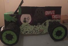 a cardboard car made to look like a grave digger with black wheels and green rims