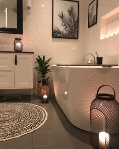 a white bath tub sitting next to a sink in a bathroom under two framed pictures