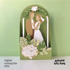 a paper cutout of a bride and groom holding each other in front of a green background