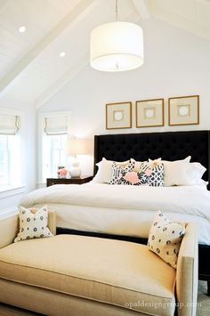 a bedroom with a bed, ottoman and pictures on the wall above it's headboard