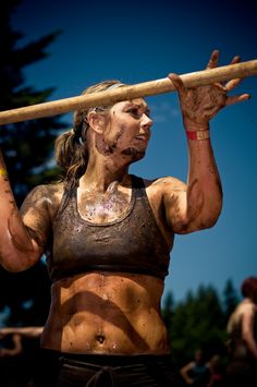 a woman holding a wooden stick in her hand while wearing mud paint on her body