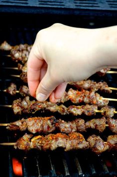 someone is cooking on a grill with skewers full of meat and sauces