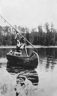 an old black and white photo of a man in a boat with a fishing pole