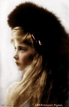 an old black and white photo of a woman with long hair wearing a fur hat