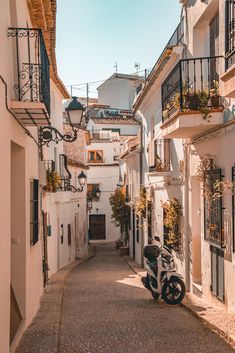 a scooter parked on the side of a narrow street in an old town