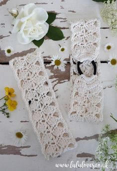 two crocheted white gloves with black bows and flowers on a wooden table next to them