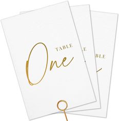 three white cards with gold foil on the front and one has a string attached to it