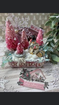 a christmas scene with pink trees and snowmen in a basket on top of a table