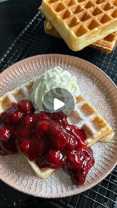 waffles and ice cream are on a plate with syrup, whipped cream and strawberry compote