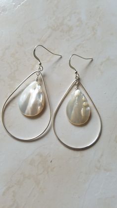 "These wonderful teardrop earrings are handmade with lustrous mother of pearl shell and sterling silver. Simple yet pop and make a statement! A mother of pearl teardrop is wire wrapped to hang down the inside of a sterling silver teardrop. These mother of pearl earrings are perfect for everyday and can also be dressed up with evening wear. Its amazing how well the white matches everything! They are available in 4 sizes, each very lightweight.  This listing is for the 2nd to largest size, the lar Teardrop Mother Of Pearl Ear Wire Jewelry, Silver Mother Of Pearl Earrings With Ear Wire, Silver Teardrop Mother Of Pearl Earrings, Pearl Drop Shell-shaped Earrings In Mother Of Pearl, Elegant Shell-shaped Mother Of Pearl Earrings, Pearl Teardrop Earrings, Aqua Earrings, Mother Of Pearl Earrings, Shell Earrings