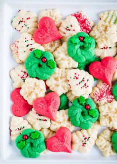 a white plate topped with cookies covered in green and red frosted hearts, sprinkles and candy