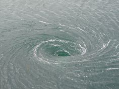 a circular object in the middle of water with waves coming up from it's center