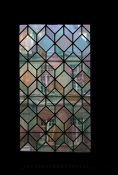 a close up of a stained glass window with buildings in the background