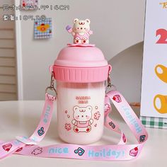 a pink and white baby bottle with a teddy bear on it's lid next to a ribbon