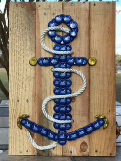 an anchor made out of blue bottle caps on a wooden pallet with white rope