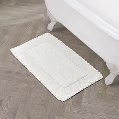 a white bath tub sitting on top of a hard wood floor next to a rug