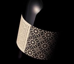 a bottle of wine is shown on a black background with an intricate pattern around it