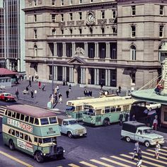 an old photo of buses, cars and pedestrians on the street in front of buildings