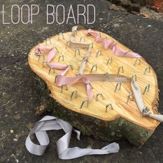 a wooden board with scissors and ribbons on it that is sitting on top of a rock