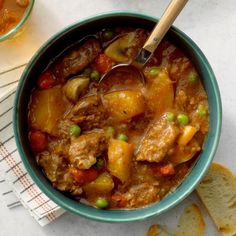 a bowl filled with stew next to slices of bread