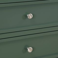 a green dresser with three drawers and two knobs on the top one drawer is open