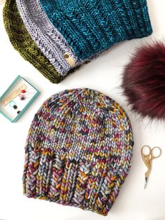 two hats, one with fur pom - pom and the other in different colors