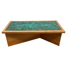 a wooden table with a green glass top on it's legs and bottom section