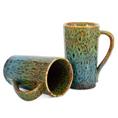 two coffee mugs sitting next to each other on a white surface, one is green and the other has brown speckles