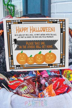 a sign that says happy halloween with candy in front of some pumpkins and other candies