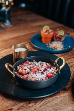 a pan filled with food sitting on top of a wooden table next to two cups