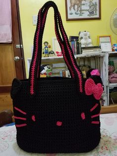 a crocheted hello kitty purse with a pink bow on the front and side