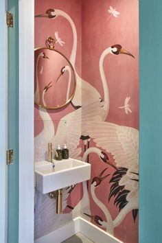 a bathroom with flamingos painted on the wall next to a white sink and mirror