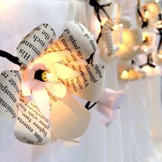 paper flowers with lights strung from them on a tablecloth draped over white cloths