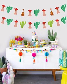 a party with cactus decorations and tassels on the wall above it is decorated with pom poms