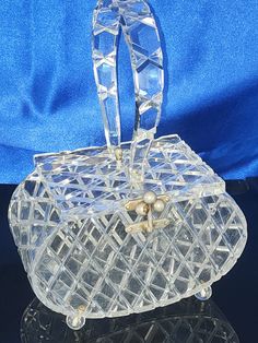 VINTAGE Clear Raised Beveled DIAMOND Cut Lucite Unqiue Shape with Clear Raised Diamod Cut Lid!! BEAUTIFUL!   EXCELLENT CONDITION MEASUREMENTS ARE APPROXIMATELY UNIQUE ROUNDED OVAL SHAPE IS 7 1/4 INCHES WIDE                         5 INCHES TALL WITHOUT HANDLE              10 1/2 INCHES TALL WITH HANDLE LID IS 4 1/4 INCHES DEEP THE PURSE IS A ROUNDED OVAL CLEAR RAISED BEVELED DIAMOND CUT LUCITE CLEAR RAISED DIAMOND CUT CARVED CUT LUCITE LID TOP  - NOT CLOUDY  CLEAR  RAISED DIAMOND CUT CARVED LUCITE HANDLE  THE LID AND LATCH SECURELY CLOSES IN PLACE.   4 CLEAR ROUND LUCITE FEET ON THE BOTTOM  NO CHIPS, NO CRACKS NO GHOSTING AND NO SMELLS THE LATCH METAL IS WORN THERE ARE MINIMAL SURFACE SCRATCHES NO DESIGNER NAME  THE PICTURES SHOW THE EXCELLENT CONDITION PLEASE EMAIL WITH ANY QUESTIONS THAN Luxury Clear Lucite Jewelry, Acrylic Purse, Pearl Bag, Designer Name, Vintage Lucite, Vintage Purses, Vintage Handbags, Vintage Bags, Vintage Hairstyles