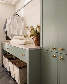 a closet with green cabinets and white shirts hanging on the clothes rack next to it