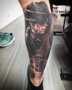 a man's leg with a black and grey tattoo design on it, featuring a woman in a hat