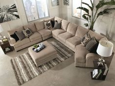 a living room with a large sectional couch and rugs on the floor in front of windows